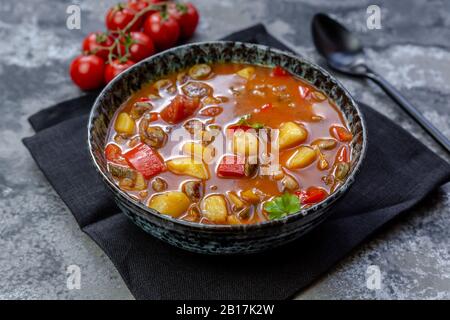 Schüssel mit Wurst Gulasch mit Kartoffeln, Tomaten, Paprika, Lauch und Petersilie Stockfoto