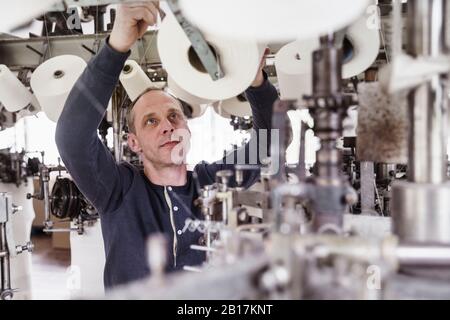 Mann, der in einer Maschine in einer Textilfabrik arbeitet Stockfoto