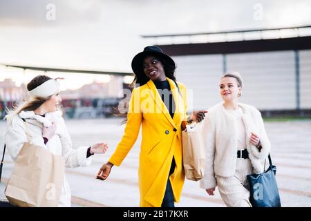 Freundinnen mit Einkaufstaschen, die in der Stadt laufen Stockfoto