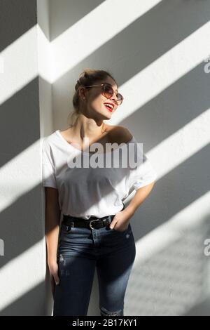 Porträt der lachenden jungen Frau mit roten Lippen und Sonnenbrille Stockfoto