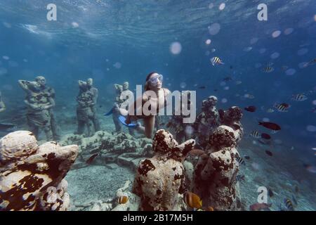 Frau schwimmt in der Nähe von Unterwasser-Skulptur von Jason deCaires Taylor, Gili Meno Insel, Bali, Indonesien Stockfoto