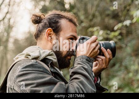 Junger Mann, der mit seiner Kamera im Wald fotografiert Stockfoto