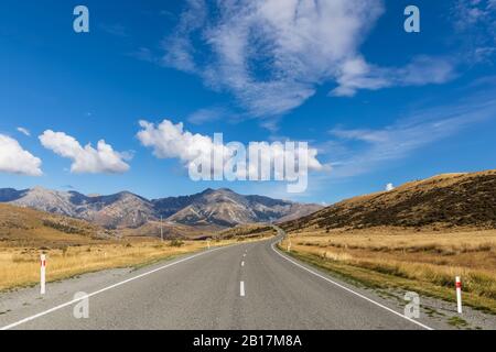 Neuseeland, Wolken über dem leeren State Highway 73 mit Bergen im Hintergrund Stockfoto