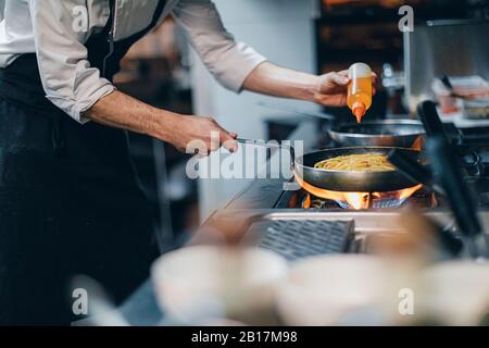 Küchenchef bereitet ein Gericht in der traditionellen italienischen Restaurantküche zu Stockfoto