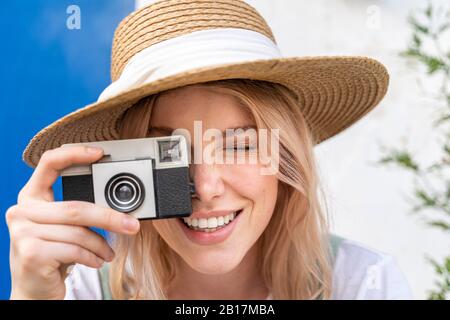 Porträt von lächelnden jungen Frau mit Strohhut, die Foto mit der Kamera Stockfoto