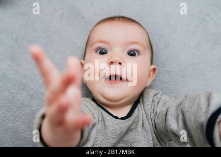 Porträt von Starring Baby Mädchen auf grauen Decke liegen Stockfoto