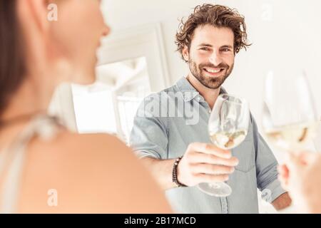 Portait von lächelndem Mann, der ein Glas Weißwein hält Stockfoto