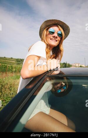 Glückliches Teenager-Mädchen, das sich aus dem Autofenster lehnt Stockfoto