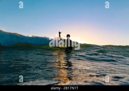 Surfer machen Surfer Zeichen sitzen auf Surfbrett, Bali, Indonesien Stockfoto