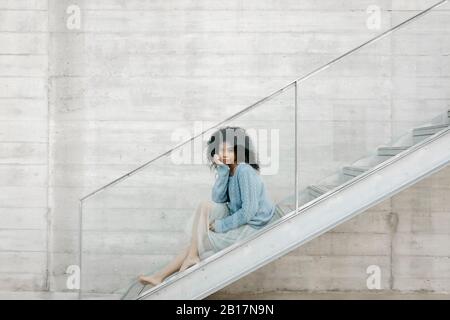 Schöne junge Frau sitzt auf der Treppe im Freien Stockfoto