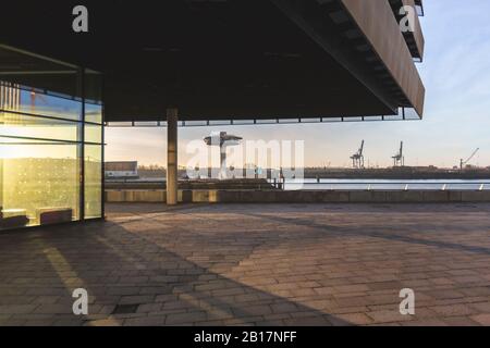 Deutschland, Hamburg, Vordach über Bürgersteig in der HafenCity bei Sonnenaufgang mit Leuchtturm Null im Hintergrund Stockfoto