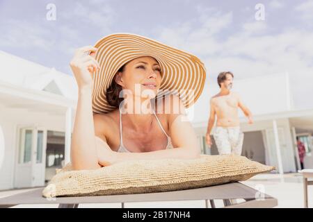 Frau auf Sonnenliege mit Mann im Hintergrund entspannen Stockfoto