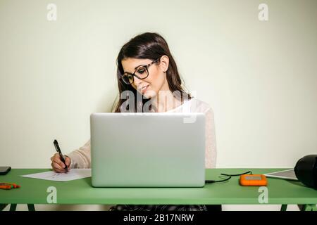 Junge Frau sitzt am Schreibtisch im Büro und zieht auf Papier Stockfoto