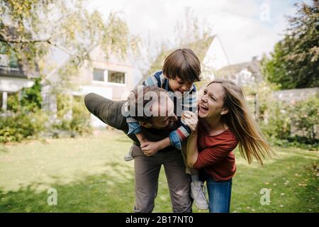 Eltern und Sohn haben Spaß und spielen im Garten Stockfoto