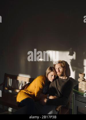 Entspanntes Paar, das zu Hause bei Sonnenlicht auf der Bank sitzt Stockfoto
