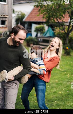 Eltern und Sohn haben Spaß und spielen im Garten Stockfoto