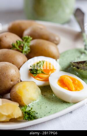 Teller mit Kartoffeln mit gekochten Eiern, Petersilie und Salsa verde Sauce Stockfoto