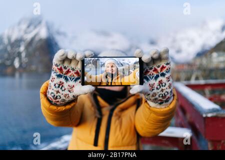 Porträt eines lächelnden Touristen, der ein selfie in Hamnoy, Lofoten, Norwegen nimmt Stockfoto