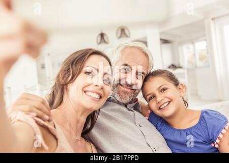 Glückliche Familie, die ein Selfie auf der Couch im Wohnzimmer macht Stockfoto
