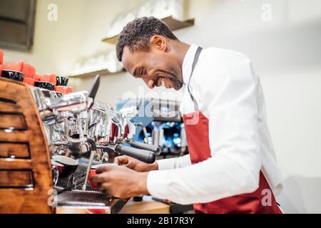 Lächelnder Barista, der einen Kaffee in einem Coffeeshop zubereitete Stockfoto