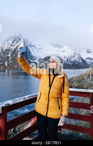 Lächelnder Tourist, der in Hamnoy, Lofoten, Norwegen ein selfie nimmt Stockfoto