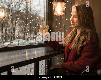 Lächelnde junge Frau mit einer Tasse Tee in einem Café Stockfoto