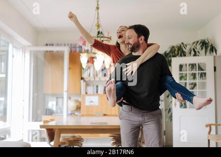 Mann, der glückliche Frau in ihrem komfortablen Zuhause zurückträgt Stockfoto