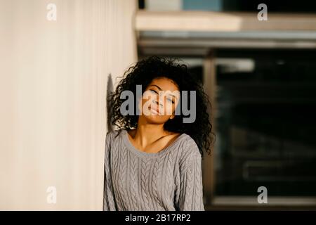 Portrait einer schönen jungen Frau, die sich an die Betonwand lehnt Stockfoto