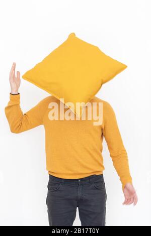 Mann, der einen gelben Pullover trägt, der sich hinter dem gelben Kissen verbirgt Stockfoto