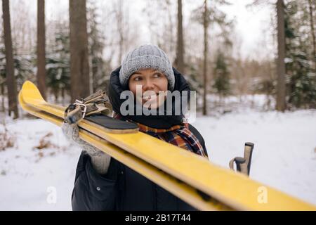 Porträt einer lächelnden Frau mit Skiern im Winterwald Stockfoto