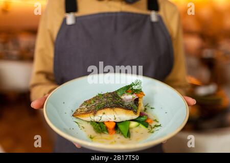 Kellnerin, die gesunden Fisch und Gemüse serviert Stockfoto