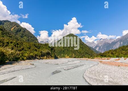 Neuseeland, Westland District, Franz Josef, landschaftlich reizvoller Blick auf den Waiho River mit bewaldeten Bergen im Hintergrund Stockfoto