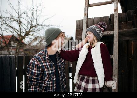 Glücklicher Vater mit Tochter auf einer Holzleiter im Winter Stockfoto