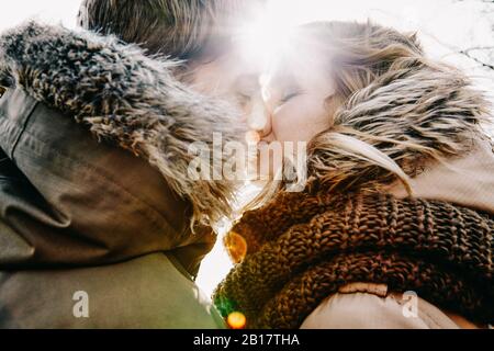Küssen junge Paar im Winter bei Hintergrundbeleuchtung Stockfoto