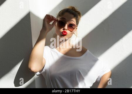 Porträt der jungen Frau mit roten Lippen und Sonnenbrille, die den Mund pfändet Stockfoto