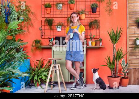 Porträt der jungen Frau mit Hund auf ihrer Terrasse Stockfoto