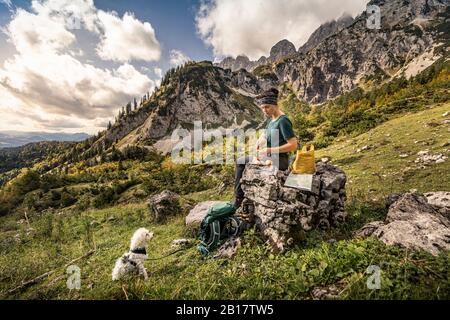 Frau mit Hund auf Wandertour am Wilden Kaiser mit Pause, Kaiser-Berge, Tyrol, Österreich Stockfoto