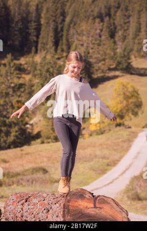 Junges Mädchen balanciert auf einem Baumstamm Stockfoto