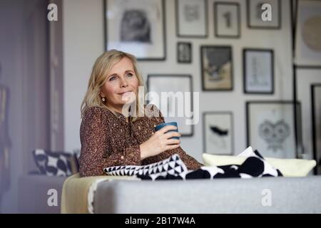 Blonde Frau zu Hause auf der Couch sitzen entspannen Stockfoto