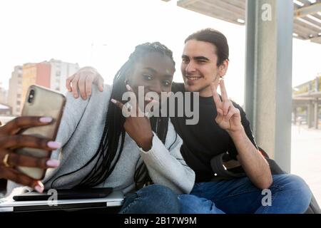 Glückliches junges Paar, das ein Selfie an der Straßenbahnhaltestelle macht Stockfoto