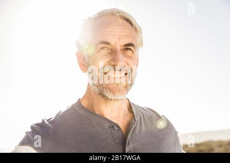 Porträt eines lächelnden grauhaarigen Mannes bei Sonnenuntergang Stockfoto