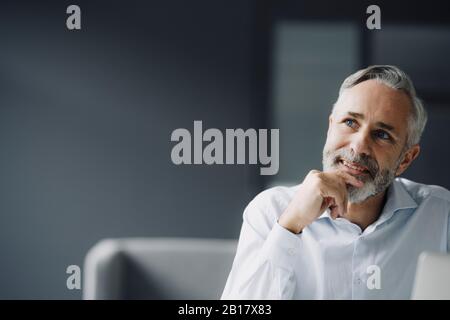 Porträt eines pensiven, reifen Geschäftsmannes in seinem Büro mit Blick auf die Ferne Stockfoto