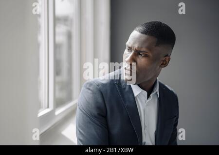 Porträt eines ernsthaften jungen Geschäftsmannes, der aus dem Fenster schaut Stockfoto