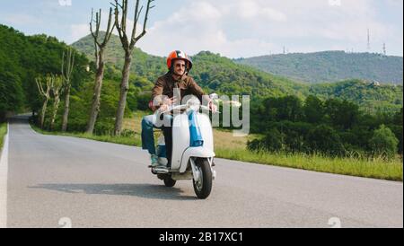 Paar reiten Vintage Motorroller auf Landstraße, Toskana, Italien Stockfoto