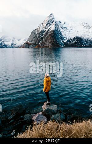 Touristen, die auf einem Felsen stehen und die Aussicht auf Hamnoy, Lofoten, Norwegen genießen Stockfoto