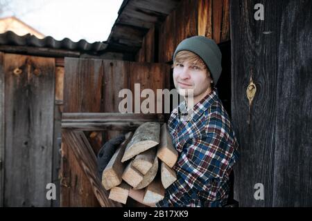 Porträt des Mannes mit wolligem Hut, der Brennholz kariert Stockfoto