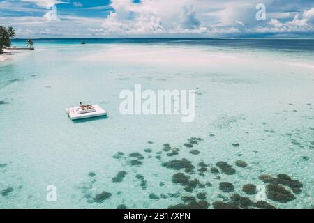 Paar liegt auf einer Plattform im Meer, Maguhdhuvaa Island, Gaafu Dhaalu Atoll, Malediven Stockfoto