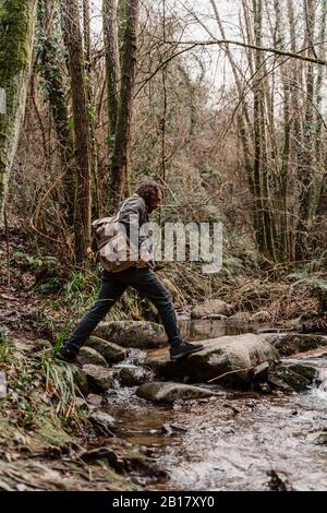 Junger Mann mit Rucksack, der Dampf im Wald überquert Stockfoto