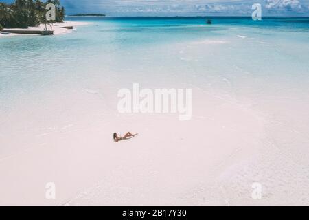 Frau, die auf einer Sandbank im Meer liegt, Maguhdhuvaa-Insel, Gaafu Dhaalu Atoll, Malediven Stockfoto