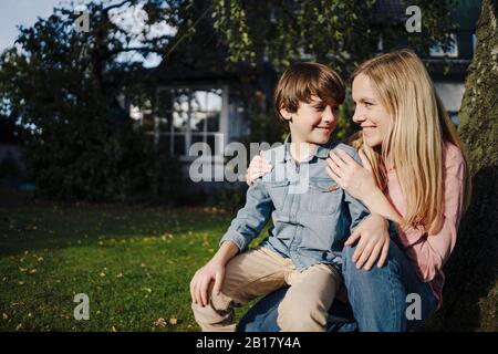 Mutter und Sohn käueln im Garten und lächeln Stockfoto